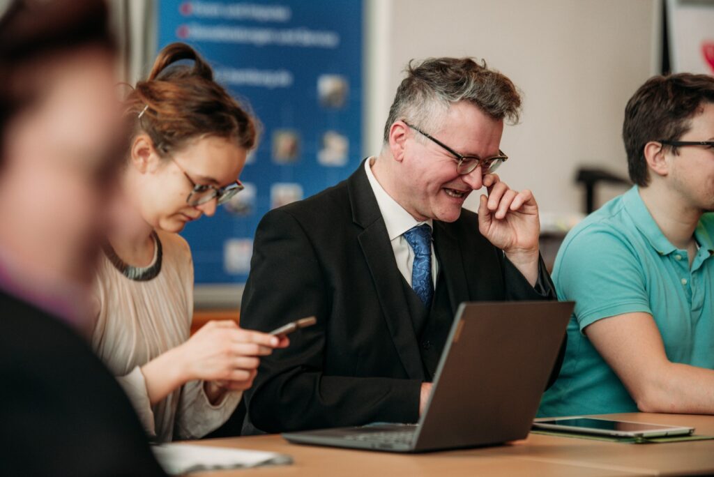 Ein Mann im Anzug lacht zur Jurysitzung des Schülerzeitungswettbewerbes der Jugendpresse Deutschland