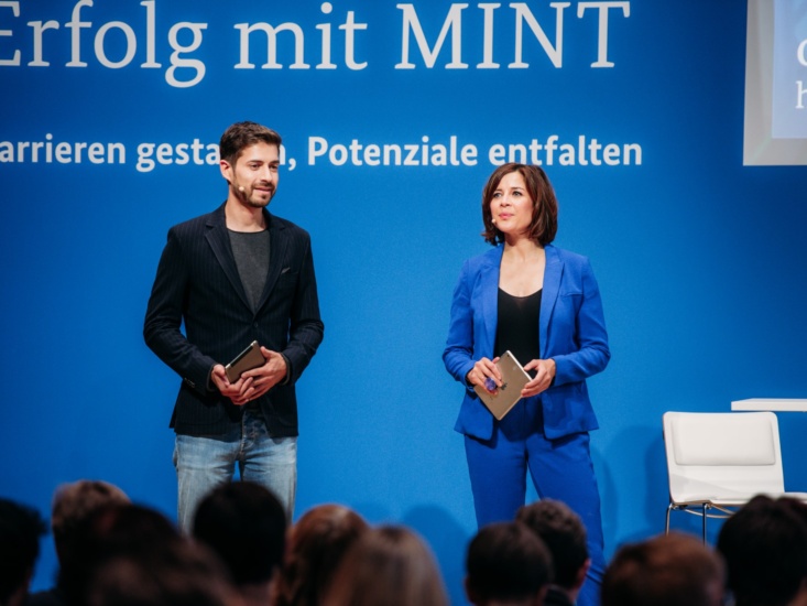 Zwei Personen moderieren vor einem Publikum am Pult bei der Transfertagung "Erfolg mit MINT" des Bundesminsteriums für Bildung und Forschung 2020