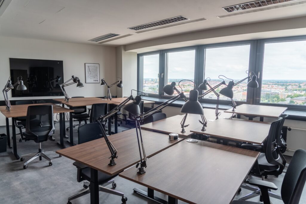 Ein Bürosraum von Workflow Coworking in Leipzig, mit Tischen und ergonomischen Stühlen und einer Panoramaaussicht über Leipzig