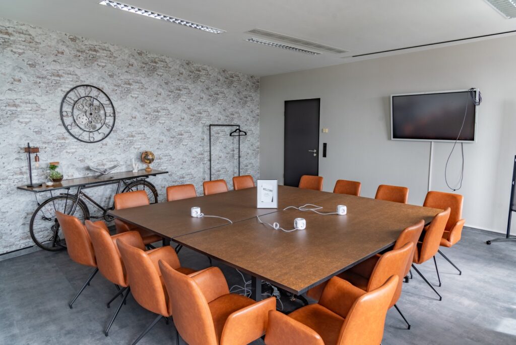 Der Meetingsraum von Workflow Coworking in Leipzig, mit Steinmauern, einem großen Tisch und Lederstühlen