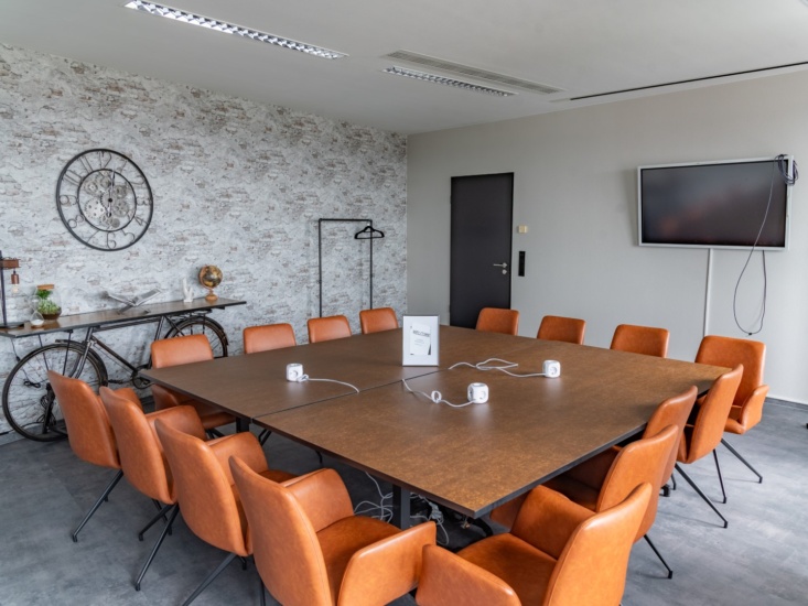 Der Meetingsraum von Workflow Coworking in Leipzig, mit Steinmauern, einem großen Tisch und Lederstühlen