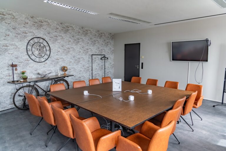 Der Meetingsraum von Workflow Coworking in Leipzig, mit Steinmauern, einem großen Tisch und Lederstühlen