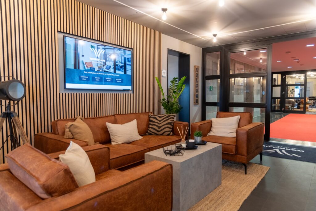 Die Lobby von Workflow Coworking in Leipzig, mit Akkustikpanelen, Teppich und Lederstühlen