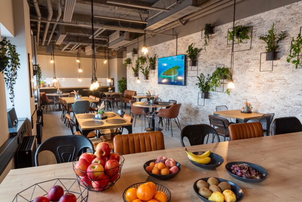 Die Gemeinschaftsküche von Workflow Coworking in Leipzig, mit Steinmauern, Holztischen und Lederstühlen