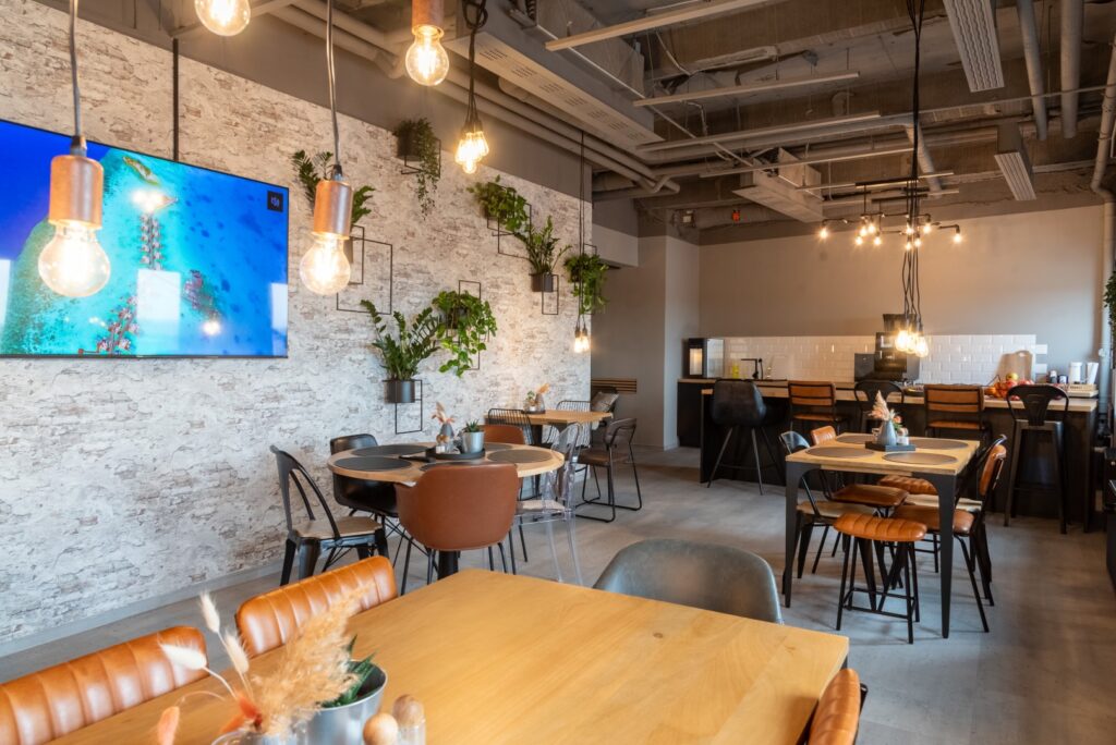 Die Gemeinschaftsküche von Workflow Coworking in Leipzig, mit Steinmauern, Holztischen und Lederstühlen