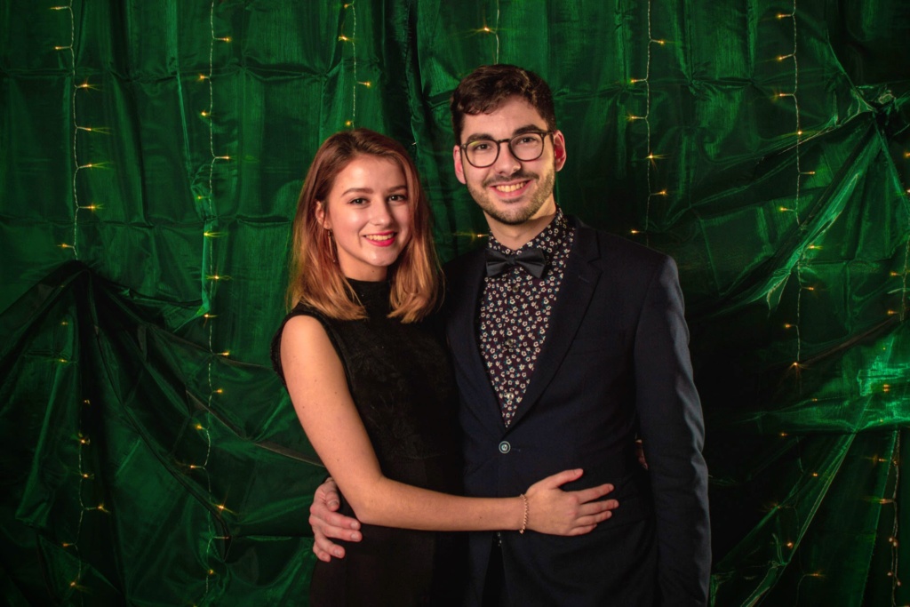 Portrait Julia Heyroth und Kurt Sauer Fotograf Kurt Sauer und seine Freundin schauen in die Kamera, tragen Abendgarderobe und stehen vor einem grünen Hintergrund