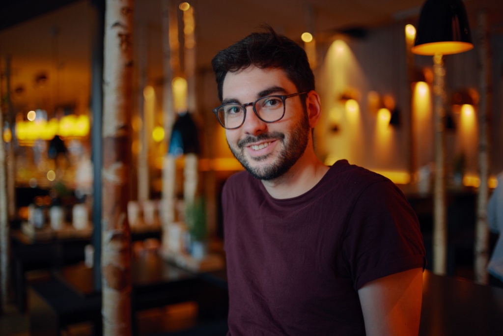 Portrait Kurt Sauer Fotograf Kurt Sauer schaut in die Kamera, trägt ein rotes T-Shirt und sitzt in einem Burger-Restaurant (Foto von Christian Schröder)