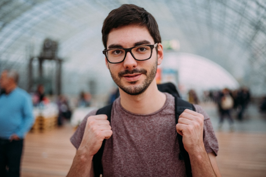Portrait Kurt Sauer Fotograf Kurt Sauer schaut in die Kamera, trägt ein rotes T-Shirt und steht in der Haupthalle der Messe Leipzig - Foto von Christian Schröder